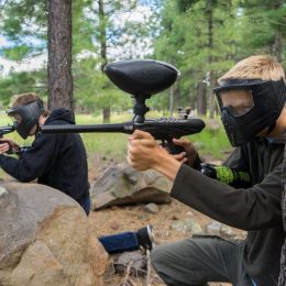 Two young men in masks aim their cheap paintball guns.